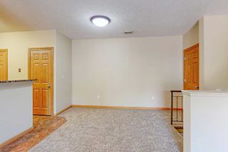A carpeted living room next to a kitchen and an open area for a dining room set up.