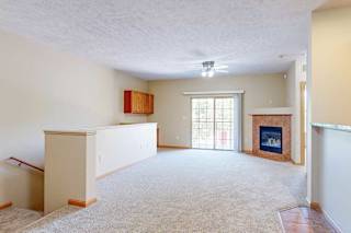 A living room with a fireplace, a sliding glass door, and a half wall around the stairs to the private entry.