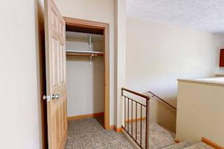 A coat closet at the top of the stairs from the private entry, with built-in shelves and hanging space.