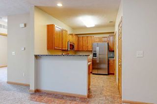 A kitchen with a bar top counter, wooden cabinets, and stainless steel appliances.