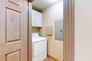 A laundry room with full-sized washer and dryer with overhead cabinets for storage.