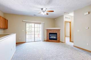 A living room with a fireplace, a ceiling fan, a built-in desk, and a sliding glass door.