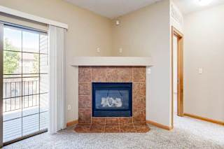 A living room with a fireplace next to the sliding glass door to the balcony.