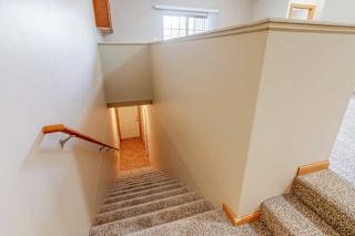 A carpeted staircase leading up from a private entry and door to an attached garage, with a wooden handrail.