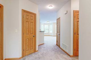A hallway leading from the front entrance to the living room, with several closet doors.