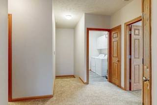 A hallway  from the front door with an open door to the laundry room, and several other doors.