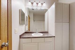 A bathroom with a vanity sink, mirror, medicine cabinet, and tall storage cabinet.
