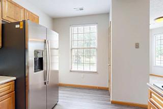 A kitchen with a stainless steel refrigerator, a large window, and wooden cabinets.