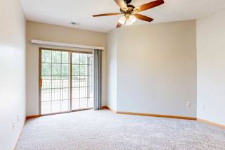 A bedroom with a ceiling fan and a sliding glass door to a balcony.
