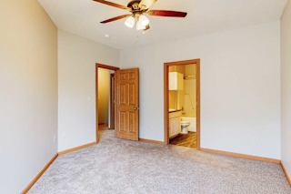 A primary bedroom with a ceiling fan, and an attached bathroom.