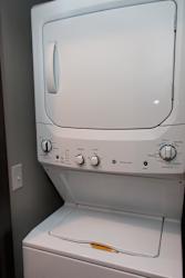 Stacked washer and dryer in closet next to extra storage closet