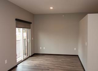 A studio living space with wooden flooring and a sliding glass door.