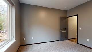 a bedroom with carpeted flooring, grey walls, and a large window with a granite windowsill