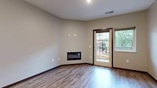 a living room with a fireplace, and a glass door and window looking out to the patio
