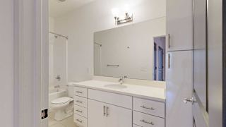 a bathroom with a granite vanity sink, mirror, and white cabinets