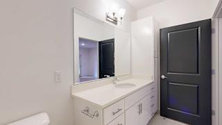 a bathroom with a white granite vanity sink and a tall white storage cabinet