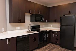 A kitchen with brown cabinets and black appliances.