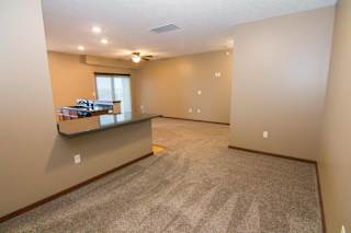 A spacious dining space or office with a carpeted floor and a window.