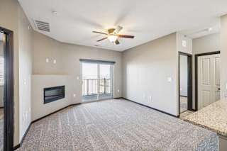 A spacious living room with a fireplace and a ceiling fan.