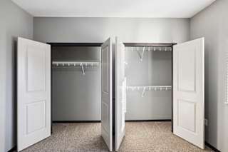 A white closet with two doors open and shelves.