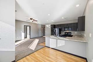 A modern kitchen with a wooden floor and a ceiling fan.