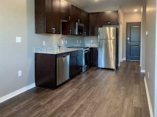 Kitchen with dark brown cabinets and matching stainless steel appliances in a studio apartment at the flats at shadow creek