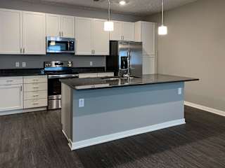 Spacious kitchen with white cabinets and large floating island with granite countertops