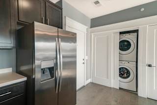 A modern kitchen with a stainless steel refrigerator and white cabinets.