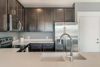 A modern kitchen with dark brown cabinets and stainless steel appliances.