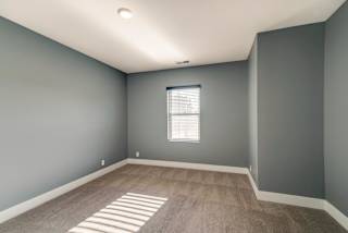 A room with a window and a carpeted floor.
