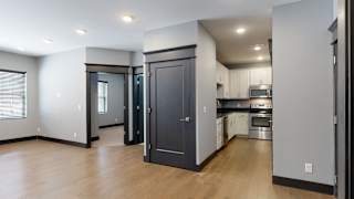 a kitchen and living room with a hardwood floor and grey walls