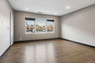 Wide windows fill this open apartment living room with natural light, complemented by gray walls, dark trim, and wood-look flooring.