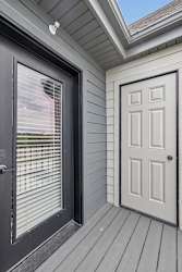 Apartment balcony with private storage closet, gray siding, and wood-look decking.