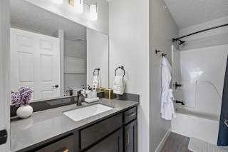 Apartment bathroom with double vanity, dark cabinetry, and blue shower curtain.