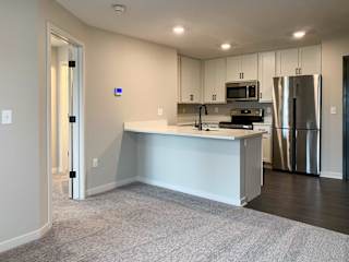 a living room connecting to a white-finished kitchen peninsula counter top
