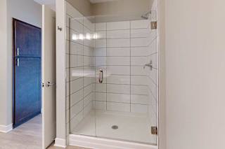 A bathroom with a tiled walk-in shower with a glass door.