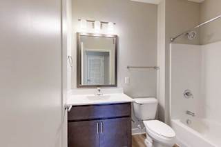 A bathroom with a marble vanity, dark wooden cabinets, and a tub shower.