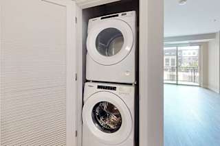 A stacked full-sized washer and dryer in a laundry closet.