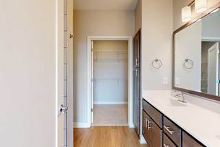 A bathroom with a double sink marble vanity and dark wooden cabinets, connected to a walk-in closet.