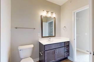 A bathroom with a marble vanity, dark wooden cabinets, connected to a walk-through closet.