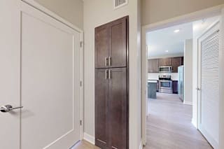 A bathroom with a a door open to the living room, and a closed linen storage cabinet.