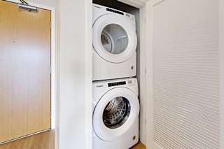 A stacked full-sized washer and dryer in a laundry closet.