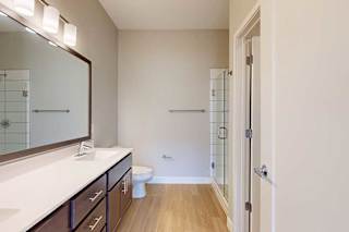 A bathroom with a marble vanity, dark wooden cabinets, and a walk-in shower.