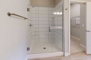 A bathroom with a tiled walk-in shower with a glass door.