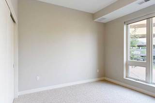 A carpeted bedroom with a floor-to-ceiling window.