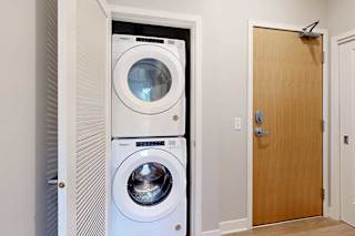 A stacked full-sized washer and dryer in a laundry closet.