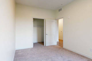 A room with a carpeted floor and a white door to the closet