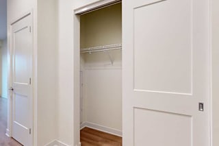White empty closet with sliding doors open, revealing a wire shelf inside.