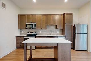 A kitchen with a moveable island and brown wood cabinets.