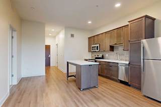 A kitchen with warm brown floors and stainless steel appliances.